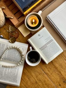 Flat lay of self-improvement books, candle, coffee mug, and pearls on a cozy table – symbolizing personal growth and reflection.
